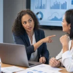 CFO and finance analyst reviewing AI spend dashboards and cost charts in a meeting room